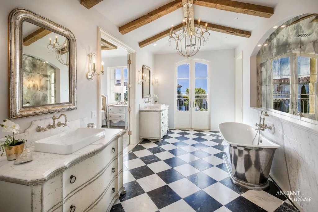 Black and white checkerboard marble bathroom floor beneath a freestanding tub and marble topped vanity