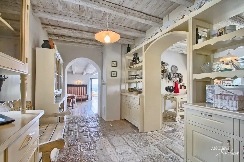Reclaimed stone floor pavers lining a rustic pantry corridor beneath whitewashed timber beams