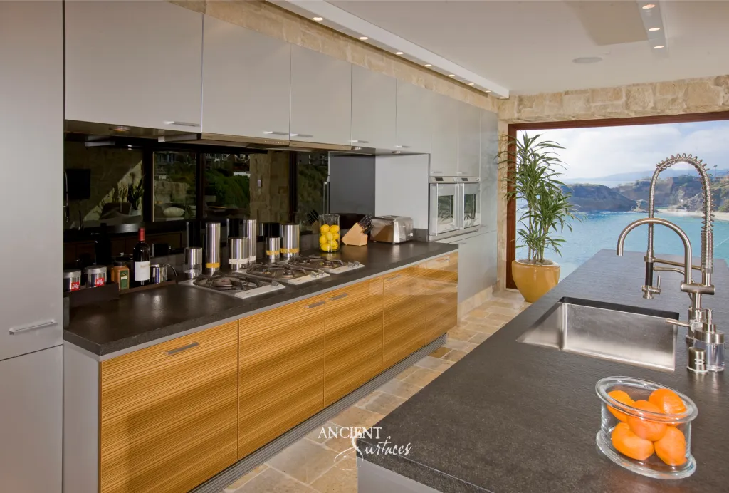 Kitchen counter and stone floor pavers opening onto an ocean view terrace at a cliffside home
