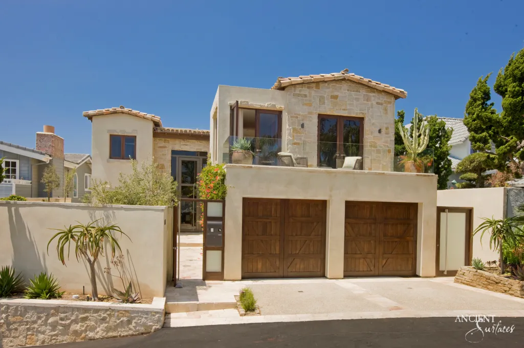 Coastal villa facade with honey colored limestone cladding framing an arched upper window